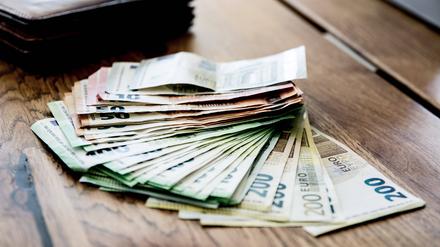 Auf einem Tisch liegen mehrere tausende Euroscheine Bargeld, in verschiedenen Größen.