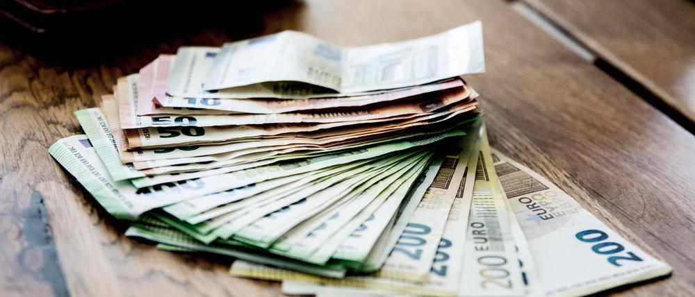Auf einem Tisch liegen mehrere tausende Euroscheine Bargeld, in verschiedenen Größen.