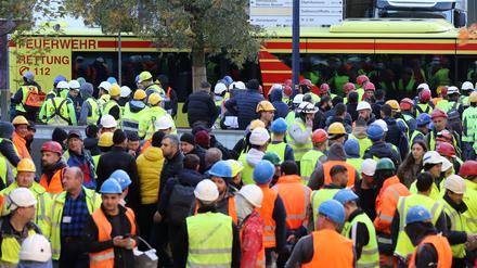 Einsatzfahrzeuge der Feuerwehr und zahlreiche Bauarbeiter stehen nach dem Unfall in der Hamburger Hafencity vor der Baustelle.