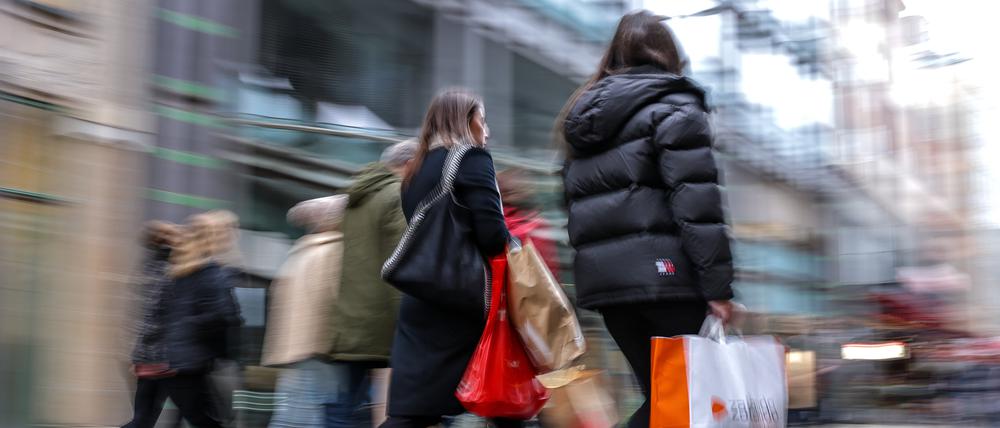 Passanten gehen mit mehreren Einkaufstüten durch die Leipziger Innenstadt.