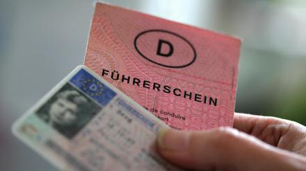 Zwei Führerscheine verschiedener Generationen hält eine Frau in der Hand. 
