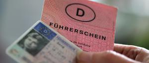 Zwei Führerscheine verschiedener Generationen hält eine Frau in der Hand. 