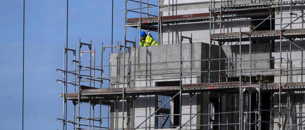 Ein Bauarbeiter steht auf einem Balkon auf einer Baustelle von einem neu gebauten Wohnhaus im Berliner Südosten. Die Nachfrage nach Baufinanzierungen ist im Zuge steigender Zinsen weiter eingebrochen. (zu dpa "Analyse: Neugeschäft mit Baufinanzierungen bricht im September ein") +++ dpa-Bildfunk +++