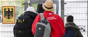 Geflüchtete betreten neben einem Schild vom Bundesamt für Migration und Flüchtlinge die Landesaufnahmebehörde Niedersachsen am Standort Braunschweig.