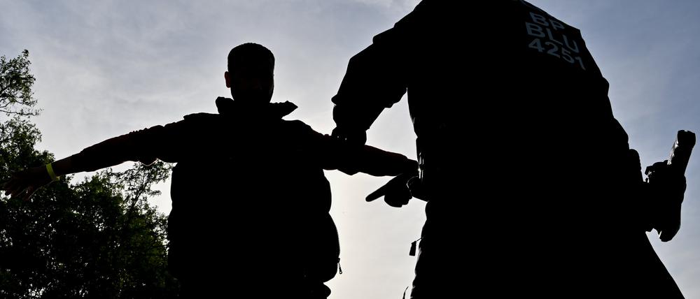 Ein unerlaubt eingereister Migranten (l) wird von einem Beamten der Bundespolizei nahe Forst (Lausitz) durchsucht.