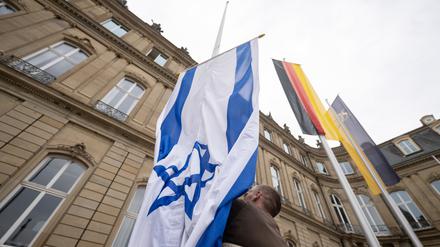 Die Flagge Israels wird von einem Mitarbeiter des Staatsministeriums Baden-Württemberg zwischen den Flaggen der EU, Deutschlands und Baden-Württembergs gehisst. (Archivbild)