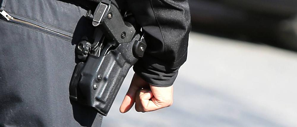  Polizist von hinten mit Schusswaffe und kugelsicherer Weste in Nahaufnahme . 
