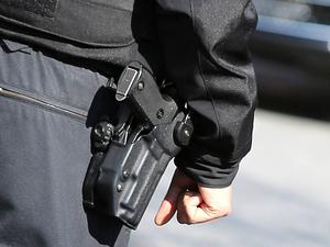 Ein Polizist von hinten mit einer Schusswaffe. (Symbolbild)