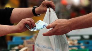 Eine Kundin erhält an einem Marktstand in München Wechselgeld und die gekaufte Ware.