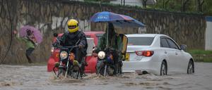 Motorbike riders wade through a waterlogged street after heavy rains in Mombasa on November 3, 2023. 