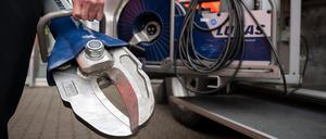 Ein Feuerwehrmann hält neben einem Fahrzeug eine hydraulische Schere in der Hand.