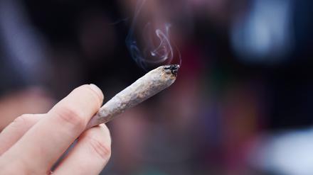 Eine Frau hält einen Joint in der Hand.