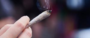 Eine Frau hält einen Joint in der Hand.
