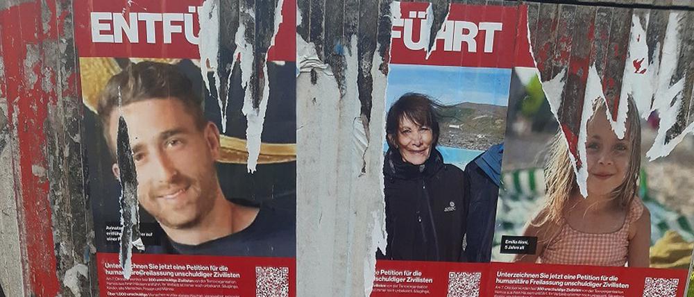 Teilweise abgerissene Plakate von Opfern des Hamas-Angriffs auf Israel  hängen auf einem Kasten in Berlin.