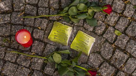 Rosen und eine Kerze liegen neben zwei Stolpersteinen in der Bahnhofstraße in Königs Wusterhausen.