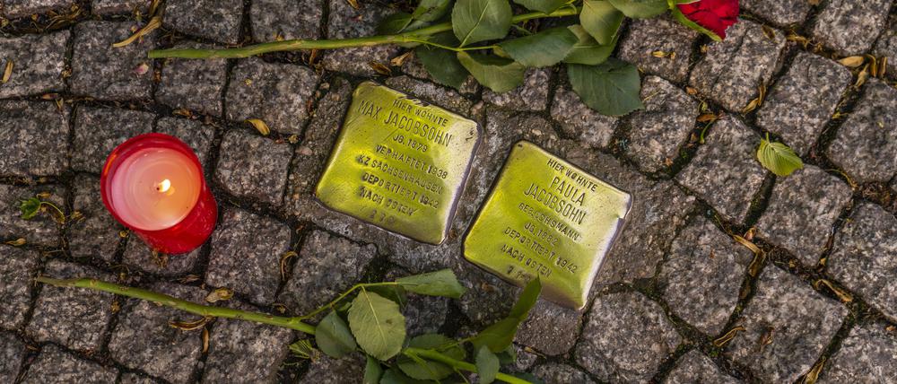 Rosen und eine Kerze liegen neben zwei Stolpersteinen in der Bahnhofstraße in Königs Wusterhausen.