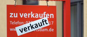 Ein rotes Schild „zu verkaufen“ ist mit dem Hinweis „verkauft“ überklebt.