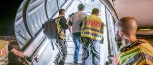 Polizeibeamte begleiten einen Afghanen auf dem Flughafen Leipzig-Halle in ein Charterflugzeug. 
