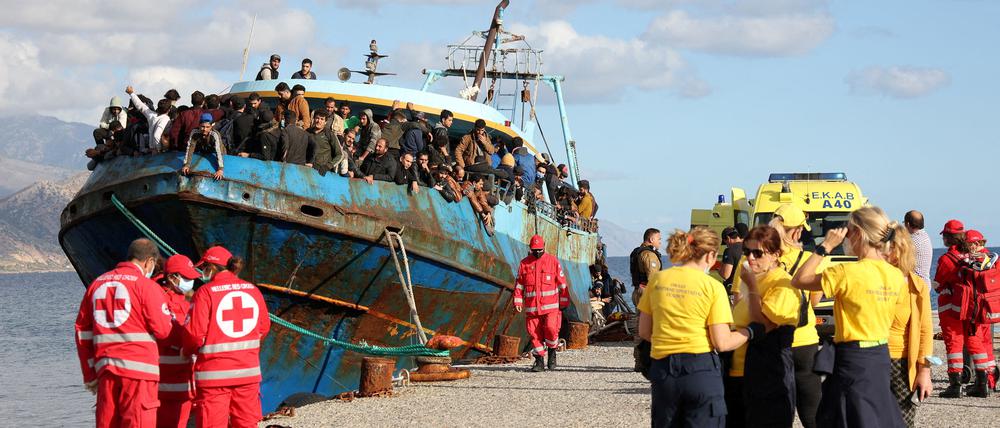 Mitarbeiter des Roten Kreuzes und Hilfsorganisationen neben einem Fischerboot mit Geflüchteten vor Kreta. 