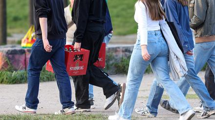 Eine Gruppe junger Erwachsener trägt Bierkästen durch den Mauerpark, Berlin Mai 2023.