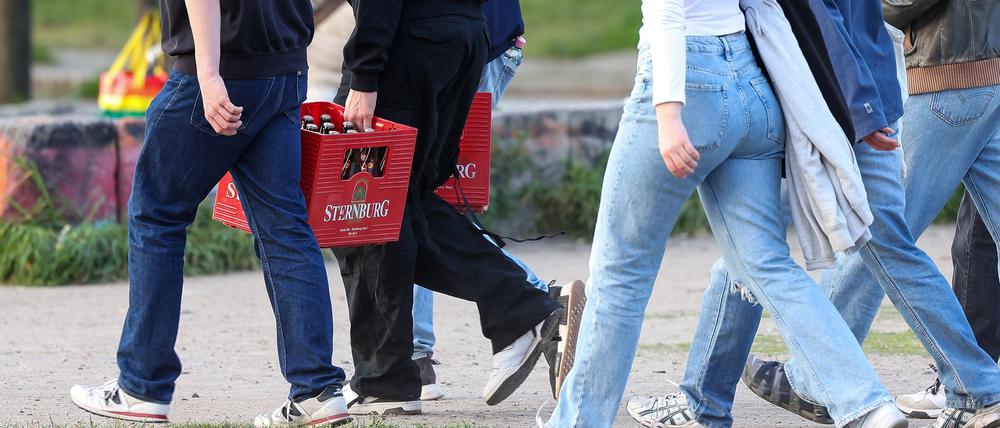 Eine Gruppe junger Erwachsener trägt Bierkästen durch den Mauerpark, Berlin Mai 2023.