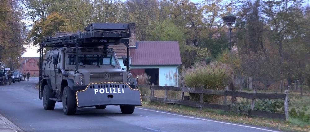 Schweres Gerät eines Spezialeinsatzkommandos der Polizei rollt durch den Ort. Nach Schüssen einer bewaffneten Person mit einem Kind auf die Polizei dauert der Einsatz im Landkreis Havelland nach rund 20 Stunden noch an. Das sagte eine Sprecherin der Polizei am Samstagvormittag. Das Kind konnte ihren Angaben noch in der Nacht gegen 1 Uhr in die Obhut des Jugendamtes übergeben werden. (Bestmögliche Qualität)