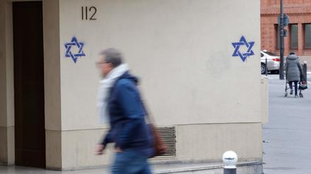 Ein Mann geht an einem Gebäude in Frankreich entlang, dessen Fassade nachts mit Davidsternen beschmiert wurde.