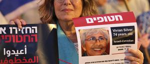 Eine Demonstrantin hält ein Vermisstenplakat für Vivian Silver hoch.