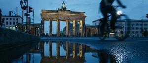 Blick auf das Brandenburger Tor. Berlins Wahrzeichen spiegelt sich bei Nacht in einer Pfütze.