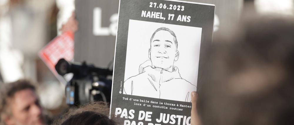 Ein Pappschild mit einem Bild von Nahel bei einer Demonstration in Frankreich