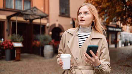 Eine Frau mit Smartphone reagiert genervt auf einen Anruf.  
