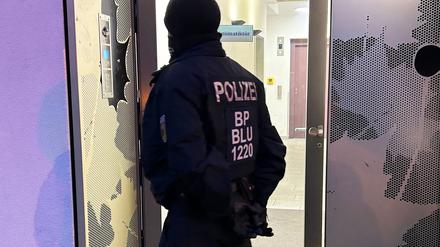 Ein Polizeibeamter steht bei einer Razzia in Berlin vor einem Gebäude. Sicherheitskräfte haben im Zusammenhang mit dem Verbot der Terrororganisation Hamas und des internationalen Netzwerks Samidoun in Deutschland mehrere Objekte in Berlin, Niedersachsen, Nordrhein-Westfalen und Schleswig-Holstein durchsucht.