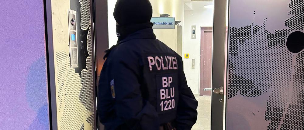 Ein Polizeibeamter steht bei einer Razzia in Berlin vor einem Gebäude. Sicherheitskräfte haben im Zusammenhang mit dem Verbot der Terrororganisation Hamas und des internationalen Netzwerks Samidoun in Deutschland mehrere Objekte in Berlin, Niedersachsen, Nordrhein-Westfalen und Schleswig-Holstein durchsucht.