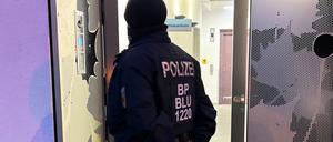 Ein Polizeibeamter steht bei einer Razzia in Berlin vor einem Gebäude. Sicherheitskräfte haben im Zusammenhang mit dem Verbot der Terrororganisation Hamas und des internationalen Netzwerks Samidoun in Deutschland mehrere Objekte in Berlin, Niedersachsen, Nordrhein-Westfalen und Schleswig-Holstein durchsucht.