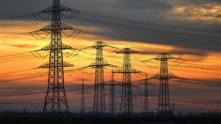 Nordrhein-Westfalen, Stommeln: Orangerot scheint das Abendlicht hinter Strommasten. 