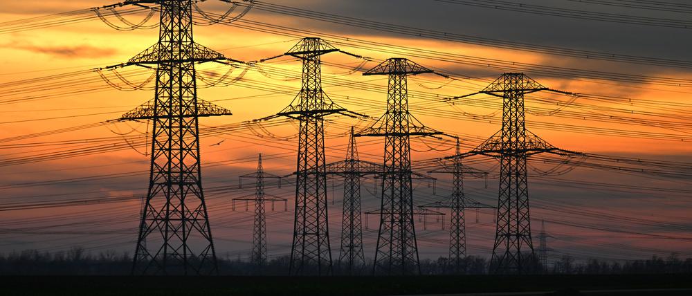 Nordrhein-Westfalen, Stommeln: Orangerot scheint das Abendlicht hinter Strommasten.