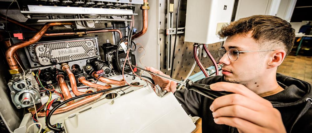 Ein Anlagenmechaniker arbeitet an einer Gastherme.