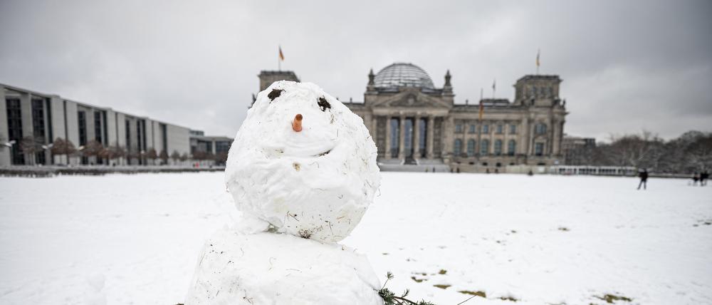 Vor dem Reichstagsgebäude steht ein Schneemann.