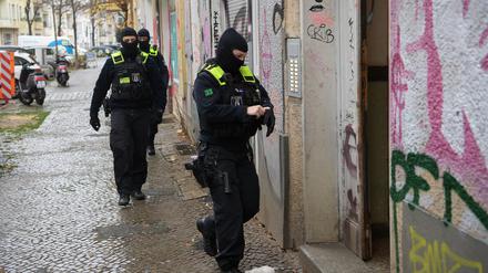 Polizeibeamte gehen bei einer Razzia in Berlin-Friedrichshain zum Eingang eines Gebäudes.