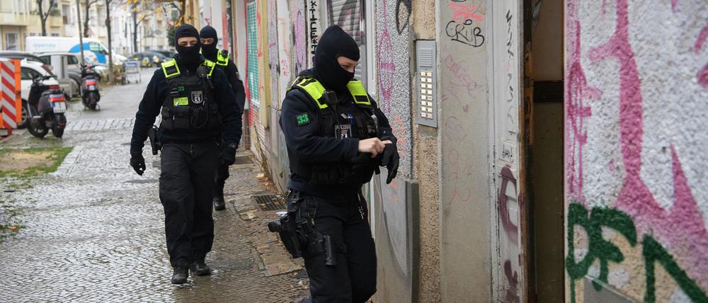 Polizeibeamte gehen bei einer Razzia in Berlin-Friedrichshain zum Eingang eines Gebäudes.