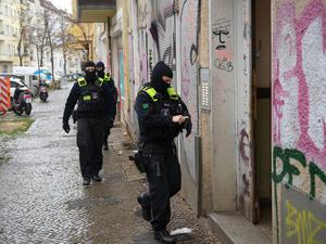Polizeibeamte gehen bei einer Razzia in Berlin-Friedrichshain zum Eingang eines Gebäudes.