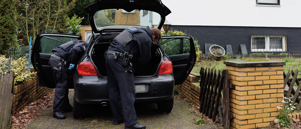 Bei einer Razzia gegen ein Schleusernetzwerk durchsuchen Polizeibeamte im niedersächsischen Garbsen ein Auto in einer Wohnsiedlung.