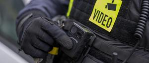 Ein Polizist schaltet die Bodycam auf seiner Uniform ein.