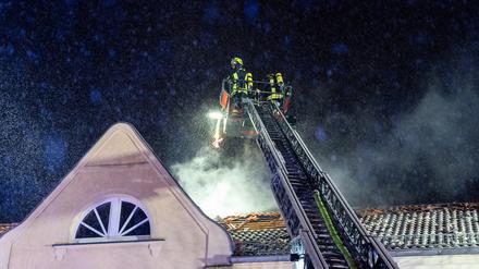 Die Feuerwehr löscht ein brennendes Dach.