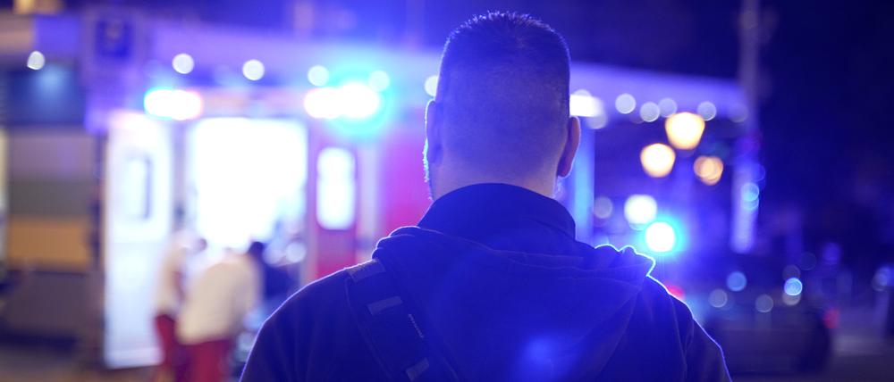 Ein Reporter steht vor einem Einsatzwagen des Rettungsdienstes.