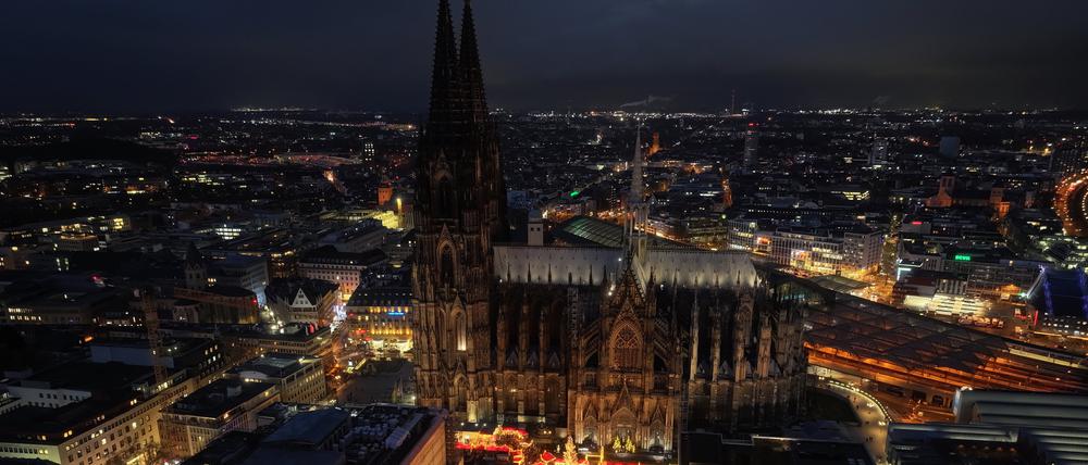 Der Kölner Dom und der Weihnachtsmarkt auf dem Roncalliplatz bei Nacht.