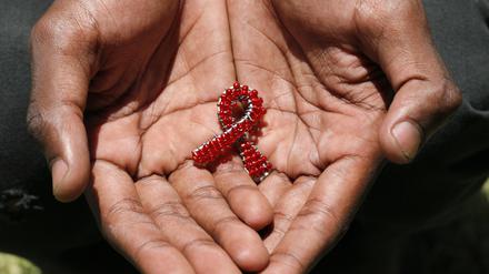 A hand made beaded AIDS symbol in the hands of a black man.