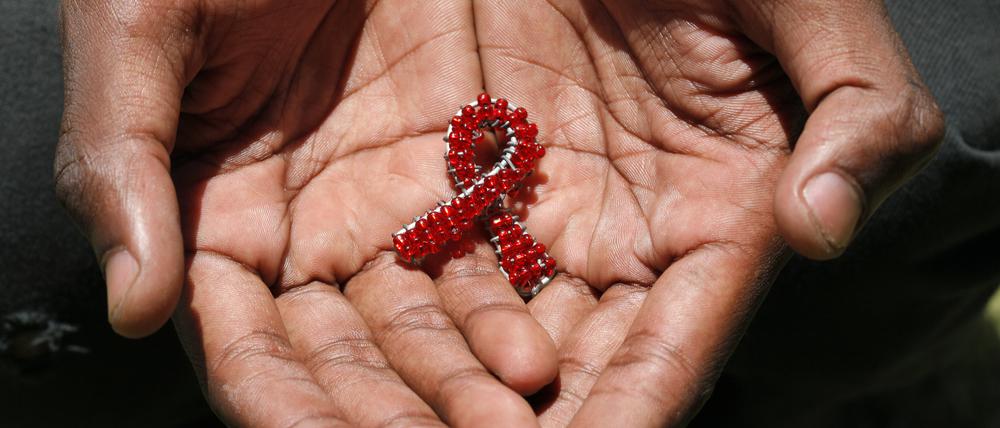 A hand made beaded AIDS symbol in the hands of a black man.