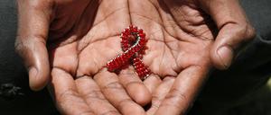 A hand made beaded AIDS symbol in the hands of a black man.