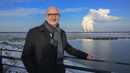 30.11.2023, Brandenburg, Cottbus: Dietmar Woidke (SPD), Ministerpräsident von Brandenburg, steht im Rahmen einer Pressefahrt auf dem Aussichtsturm am Rand der Cottbusser Ostsee vor der Kulisse des Kaftwerkes Jänschwalde. Foto: Soeren Stache/dpa +++ dpa-Bildfunk +++